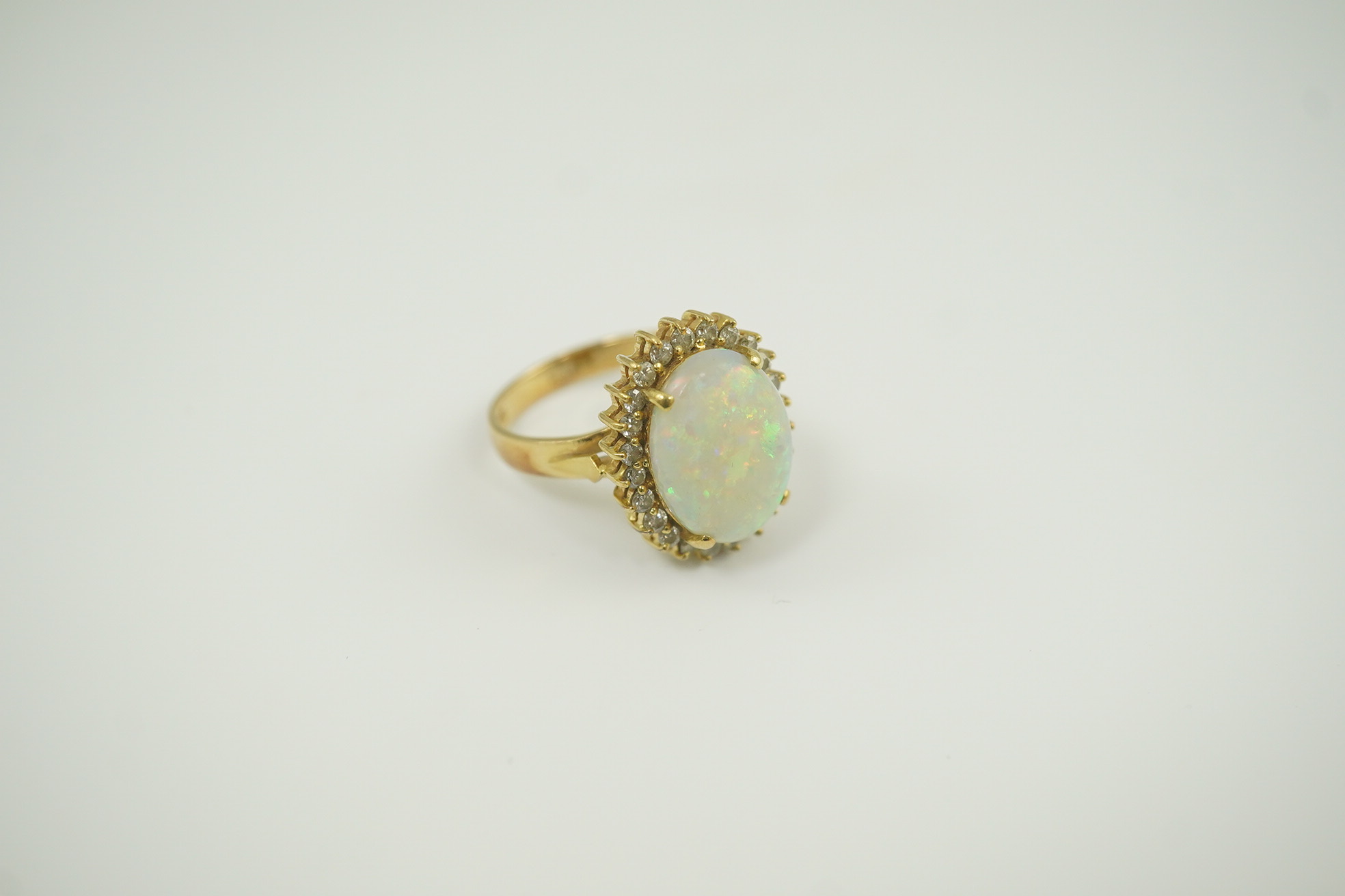 An 18k gold, white opal and diamond set oval cluster ring